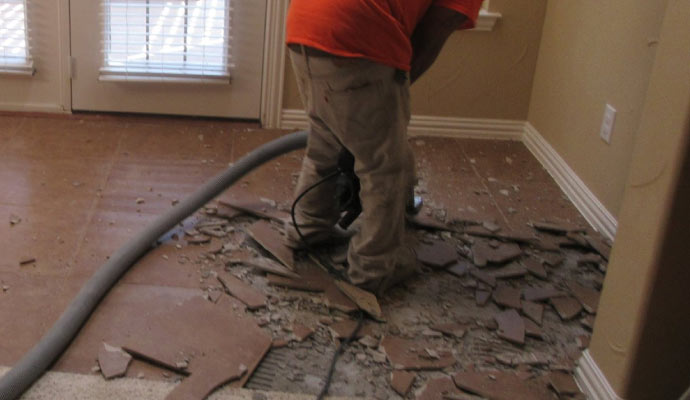 A person removing tile on the floor