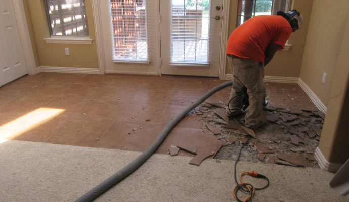 Person removing tiles from room floor