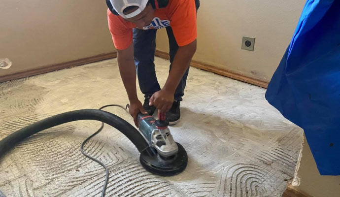 person smoothing surface with floor sander