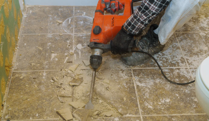 person removing floor tiles with power tool.